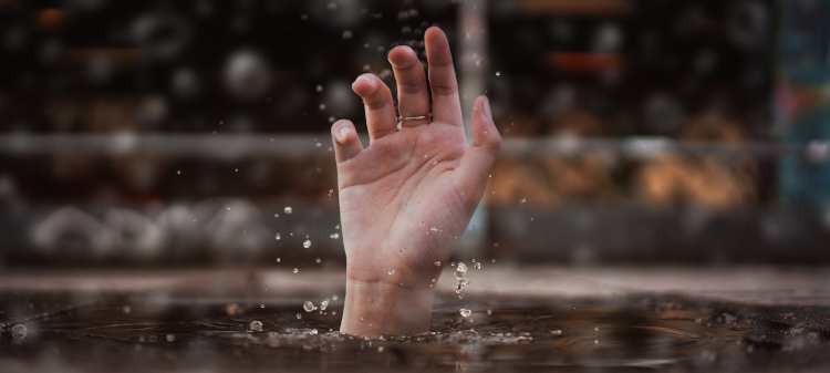 person's hand sticking out above surface of water